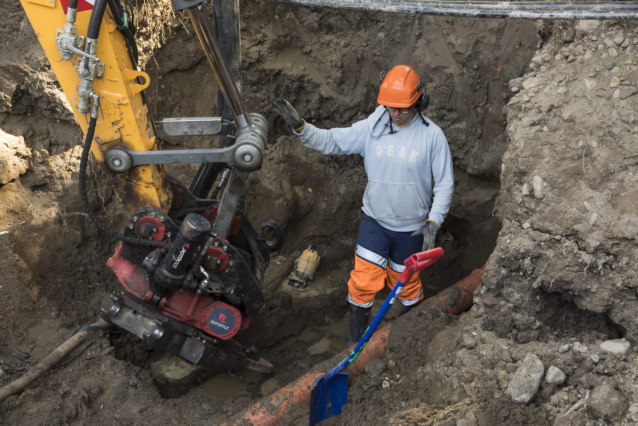 Työmies korjaa vesijohtoa syvässä kaivanteesssa.
